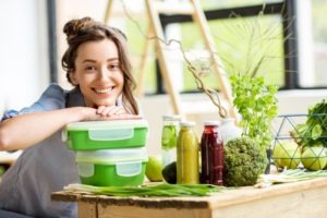  Portrait of a young smiling woman with green lunch boxes indoors